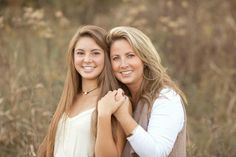 two beautiful young women standing next to each other in a grassy field with tall grass