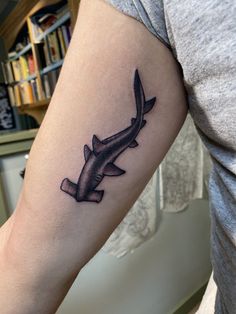 a tattoo on the arm of a person with a shark tail and knife in it