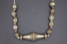 Antique, authentic and used necklace with metal beads from South Nepal, Terai Area. These Necklaces have been used by the Tribal Village Women ( Rana Tharu Tribe) as adornment. Ten antiques matched tribal silver (silver alloy) beads of collared shape and a traditional tribal silver pendant of biconical shape. Collectible and useful as jewelry supplies. Average beads measures/wt: 21 x 12 mm/9.6g Pendant measures/wt: 66.3 x 23.2 mm/28.1g Total Weight: 124 grams. Origin: Nepal Antique Silver Jewelry With Polished Beads, Vintage Silver Beaded Necklaces For Festive Occasions, Traditional Necklaces With Spacer Beads For Festivals, Traditional Silver Necklaces With Spacer Beads, Elegant Silver Beaded Necklace For Ceremonial Use, Elegant Silver Beaded Necklace For Ceremonial Occasions, Handmade Silver Temple Necklace With Round Beads, Traditional Sterling Silver Jewelry With Spacer Beads, Traditional Silver Jewelry With Spacer Beads