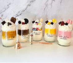 four jars filled with desserts sitting on top of a counter next to a copper bell