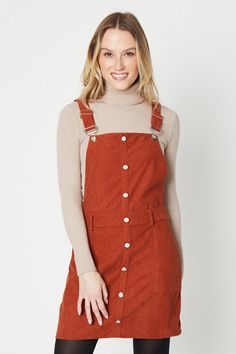 Button-through front bib with metallic buttons   Front bib pocket and two back patch pockets   Adjustable shoulder straps with buckle fastening   A-line silhouette in textured corduroy fabric  This cord dungaree mini dress from Oasis offers feminine flair with its soft pastel hue and flattering A-line silhouette. Crafted from textured corduroy fabric, it features a front bib with a pocket and metallic button closure that adds interest. Adjustable shoulder straps allow a customisable fit, while two back patch pockets provide functional detail. Style this versatile dress for day or night occasions. Its short length pairs perfectly with opaque tights and ankle boots for daytime wear. For evenings out, match with strappy heels and a leather jacket. The soft corduroy texture layers beautiful