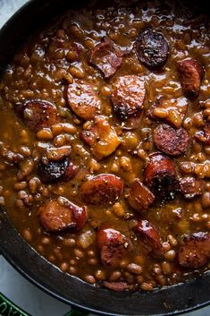 beans and sausage are cooked in a skillet on the stove top, ready to be eaten