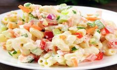 a white plate topped with pasta salad on top of a wooden table