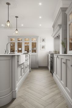 a large kitchen with white cabinets and wood flooring on the walls, along with herringbone floors