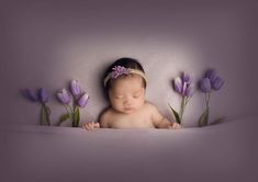 a baby is laying down with purple flowers