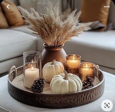 a tray filled with candles and pumpkins on top of a white couch next to pillows