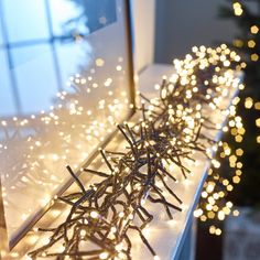 a close up of lights on a window sill with a christmas tree in the background