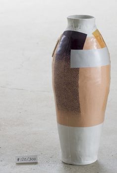 a white and brown vase sitting on top of a cement floor