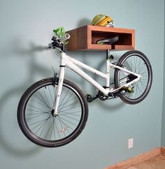 a bike hanging from the wall with a shelf on it's side and a helmet attached to the back