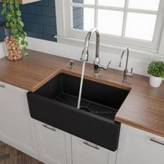 a kitchen sink sitting under a window next to a potted plant on top of a counter