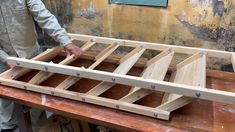 a man standing next to a wooden table with two pieces of wood on top of it