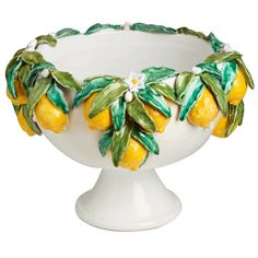 a white bowl with lemons and leaves painted on the side, in front of a white background