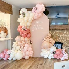 a baby is in bloom balloon arch with pink, white and peach balloons on it