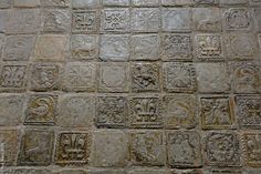 an old stone wall with many small squares and designs on the tiles, all in different sizes