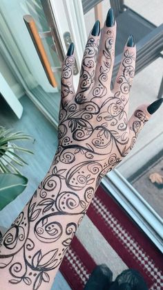 a woman's hand with black and white designs on it, next to a door