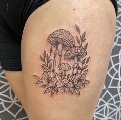 a woman's thigh with mushrooms and flowers tattoo on her leg, in black and white