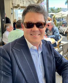 a man wearing sunglasses sitting at an outdoor table