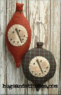 two clocks are hanging on the side of a wooden wall next to a red vase