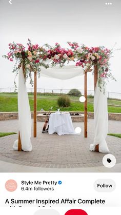 an outdoor wedding setup with flowers and draping on the top, white table cloth draped over it