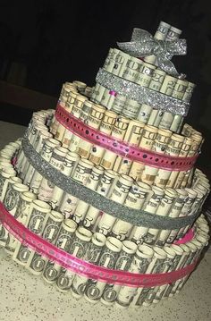 a cake made out of stacks of money on top of each other with pink ribbon