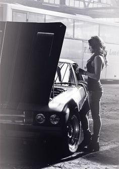 a woman standing next to a car with the hood open