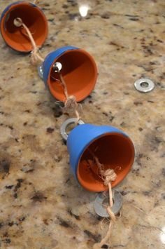 three blue plastic cups are tied up on a counter top with coins and twine