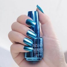 a woman's hand holding a blue nail polish bottle with metallic foil on it