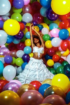 a woman in a white dress surrounded by balloons