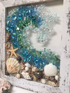 an old frame with sea glass and seashells on the bottom is displayed in front of a starfish