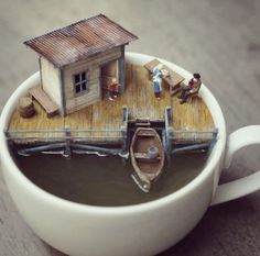 there is a miniature house on top of a coffee cup with people in the boat