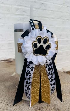 a white and black dog paw print ribbon on a coffee cup with a gold glitter bow