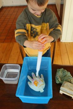 a young boy sitting at a table with a toothbrush in his mouth and soap