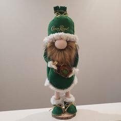 a green and white stuffed animal wearing a green hat with gold chains on it's neck