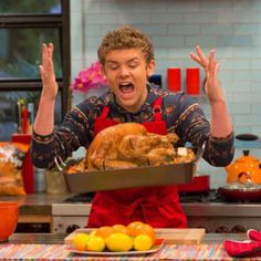 a man in an apron holding a tray with a turkey on it and hands up