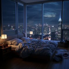 a bedroom with a large window overlooking the city at night, and an unmade bed