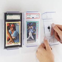 a person is playing with two baseball cards on the wall and one has a phone in it