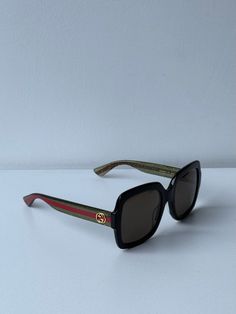 Nuevas gafas de sol negras Gucci GG0036SN 002.

 Con patas brillantes con rayas Gucci verdes/rojas y logotipos de metal dorado en las patillas.

 Lentes de color marrón oscuro 100% con protección UV.

 Forma cuadrada clásica para cualquier tamaño o forma de rostro.

 Súper ligero y perfecto para el uso diario.

 Viene con estuche, bolsa de satén a juego, tela y toda la documentación.

 Talla 54-22-140.

 100% auténtico y sin uso.

 Precio de venta al público $400. Gucci Green Sunglasses With Mirrored Lenses, Gucci Green Polarized Sunglasses, Gucci Green Sunglasses With Uv Protection, Luxury Green Gucci Sunglasses, Gucci Red Sunglasses With Uv Protection, Red Gucci Sunglasses With Uv Protection, Gucci Casual Green Sunglasses, Casual Green Gucci Sunglasses, Gucci Multicolor Sunglasses