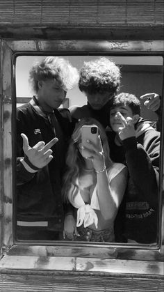 two men and a woman taking a selfie in front of a mirror with their cell phones