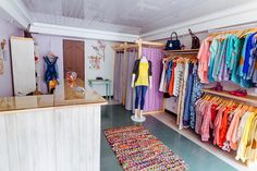 a clothing store filled with lots of different colored shirts and handbags on hangers