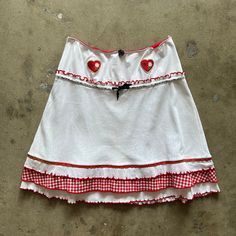 Adorable white and red skirt by Vive Maria. Features mixed pointelle and gingham fabrics, heart patches, tiered hemline, and elastic waist band. Has tiny stain (see photos). Love this for a night out , casual or dressed up. Designer - Vive Maria No size marked. Best fits Medium. Fabric has stretch. Approximate measurements: Waist/Hip: 15" Length: 20.5" White Patchwork Mini Skirt, Fitted White Bottoms With Patchwork Details, Cute Fitted White Skirt, White Cotton Retro Mini Skirt, Fitted Gingham Tiered Skirt, Retro Fitted White Skirt, Retro White Lined Mini Skirt, Vintage White Mini Skirt, White Retro Mini Skirt