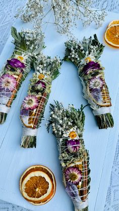 dried flowers and orange slices are arranged on a blue tablecloth with white doily