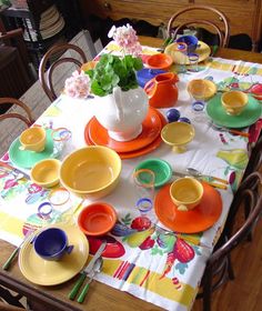 the table is set with colorful plates and cups