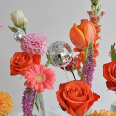 there are many flowers in the vase with disco ball on it and one is orange