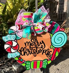 a merry christmas door hanger with candy canes and bows on it in front of a house