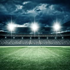 an empty soccer stadium at night with floodlights on the stands and green grass field