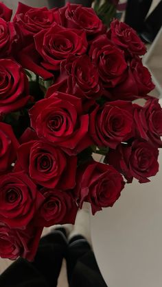 a vase filled with red roses sitting on top of a white table next to a mirror