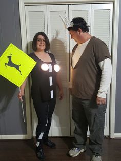 a man and woman standing next to each other in front of a door with lights on