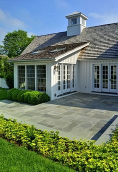 a white house with an open patio and large windows on the roof, surrounded by greenery