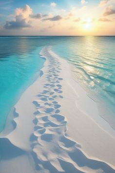 the sun is setting over an empty beach with footprints in the water and sand on the shore