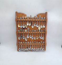 a wooden rack with spoons and other kitchen utensils hanging on the wall